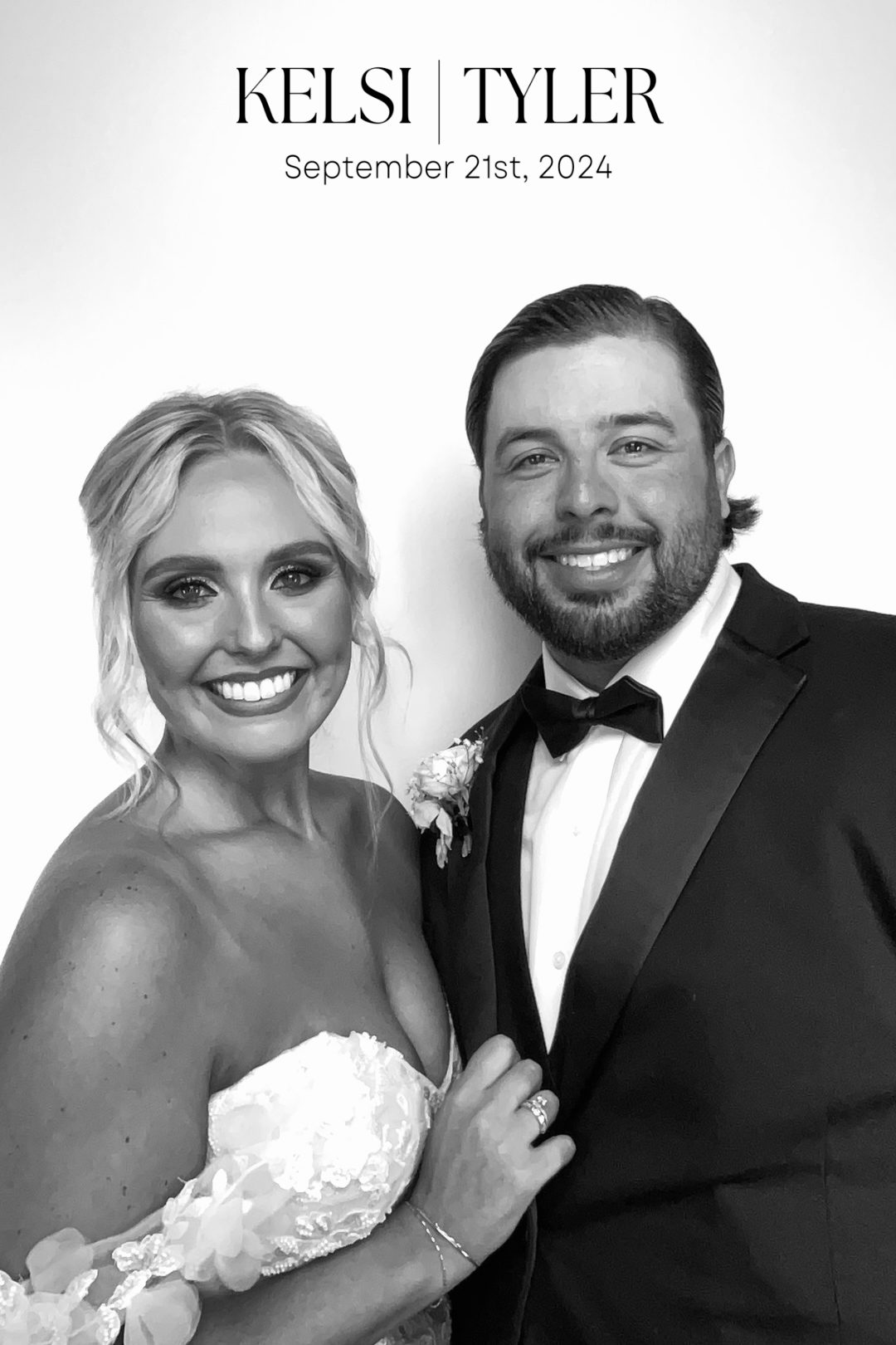 Black-and-white photo booth print of a bride in a lace gown and a groom in a tuxedo